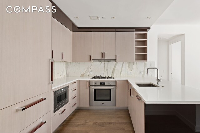 kitchen with sink, dark hardwood / wood-style flooring, decorative backsplash, kitchen peninsula, and stainless steel appliances