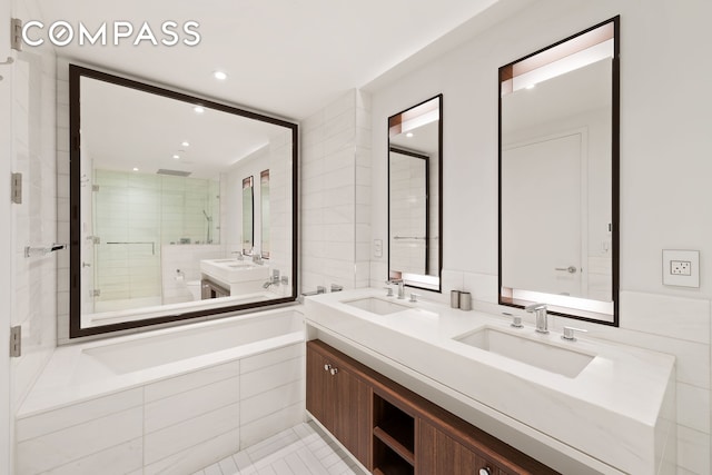 full bathroom featuring double vanity, a garden tub, a shower stall, and a sink