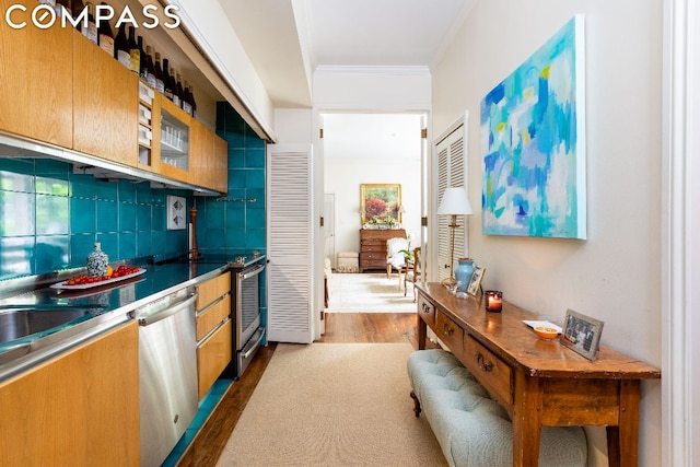 kitchen featuring dark countertops, crown molding, decorative backsplash, dark wood-style floors, and stainless steel appliances