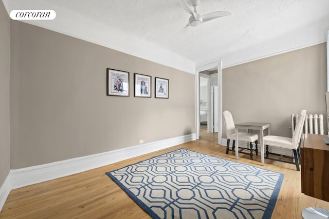 sitting room with hardwood / wood-style flooring, a textured ceiling, radiator, and ceiling fan