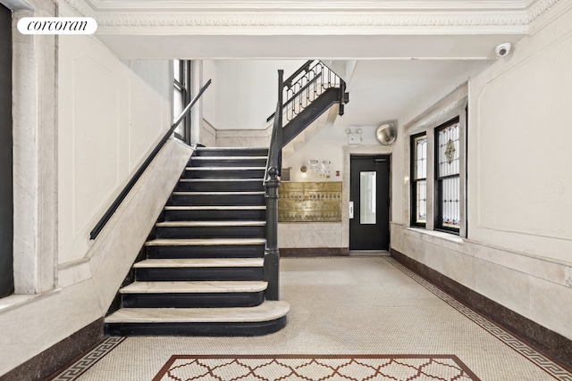 stairs featuring crown molding and elevator