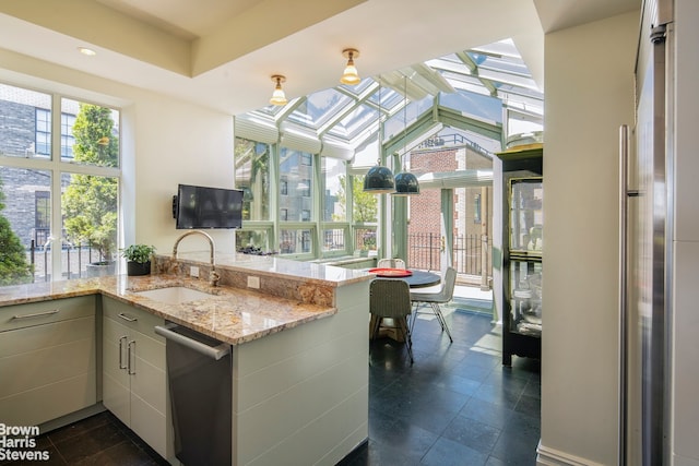 kitchen with a skylight, appliances with stainless steel finishes, kitchen peninsula, and sink