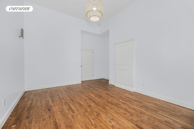 unfurnished room with hardwood / wood-style flooring and a towering ceiling