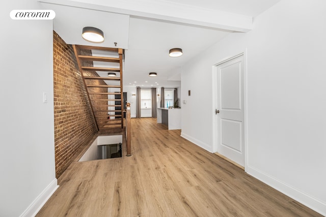 hall with light hardwood / wood-style flooring and brick wall