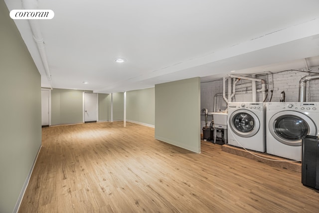 washroom featuring independent washer and dryer, brick wall, and light hardwood / wood-style floors