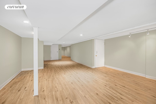 basement featuring rail lighting and light wood-type flooring