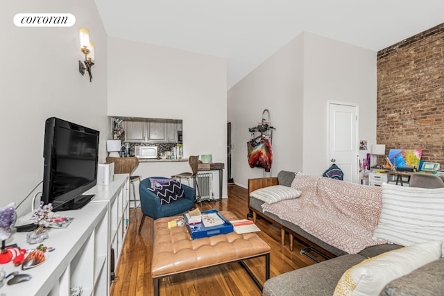 living room with hardwood / wood-style floors and brick wall