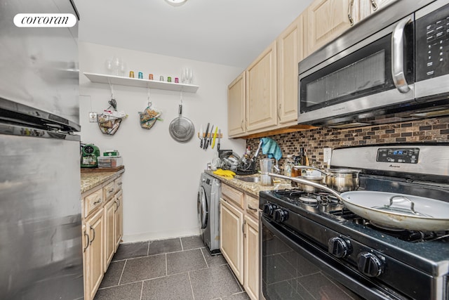 kitchen with light stone counters, washer / dryer, gas stove, and backsplash