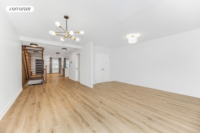 unfurnished living room with a notable chandelier and light hardwood / wood-style floors