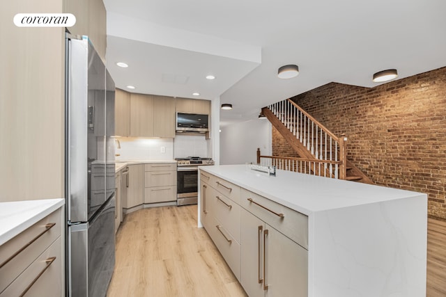 kitchen with tasteful backsplash, light hardwood / wood-style flooring, light brown cabinets, appliances with stainless steel finishes, and a kitchen island