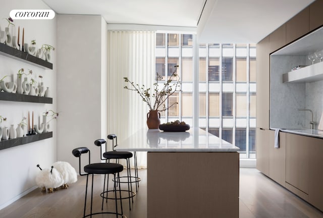 kitchen with a healthy amount of sunlight, sink, a kitchen breakfast bar, and light wood-type flooring