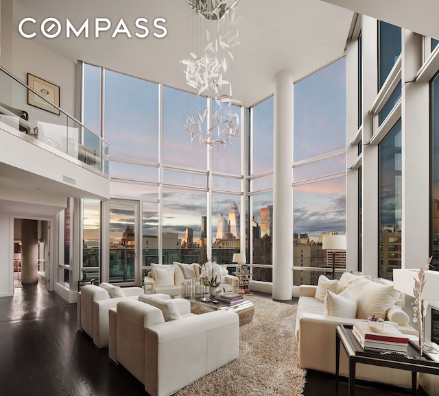 living area with dark wood-style floors, a wealth of natural light, a wall of windows, and an inviting chandelier