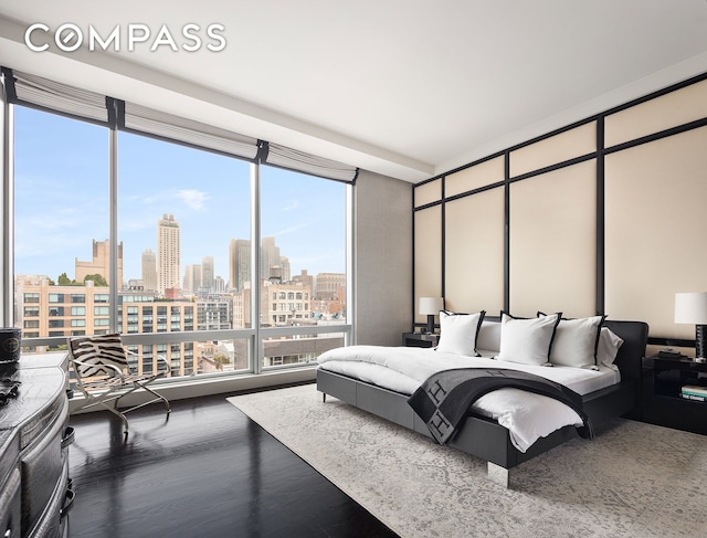 bedroom with expansive windows, a view of city, and wood finished floors