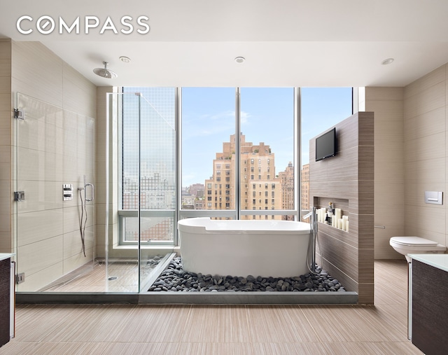 bathroom featuring tile patterned floors, a soaking tub, a shower stall, and toilet