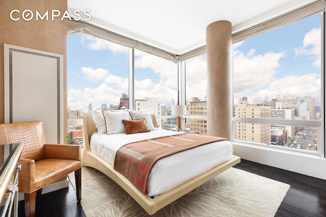 bedroom with a view of city and wood finished floors