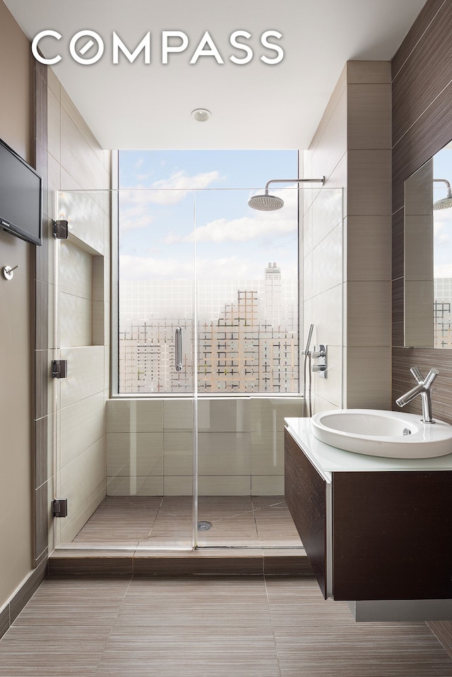 full bath featuring vanity, a shower stall, and a view of city