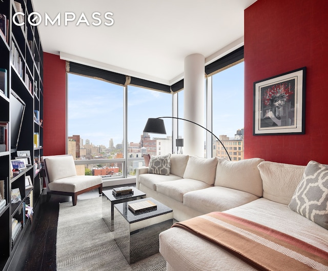 living area featuring a healthy amount of sunlight, a view of city, a wall of windows, and wood finished floors