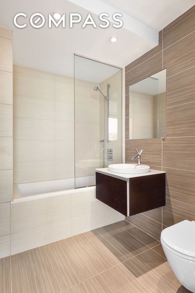 bathroom with tile patterned floors, toilet, tile walls, and vanity