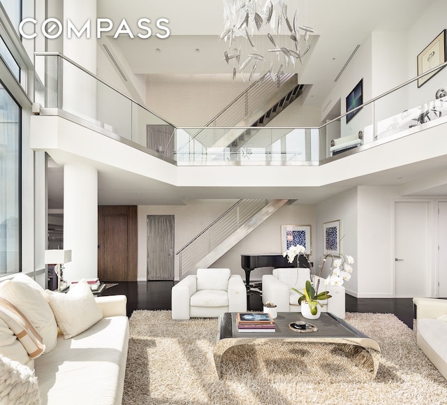 living room with stairway, wood finished floors, and a towering ceiling