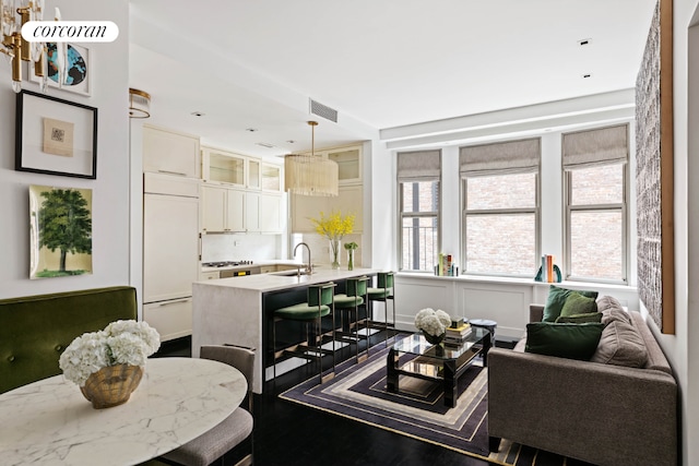 living area with dark wood-style flooring, a healthy amount of sunlight, and visible vents