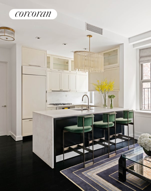 kitchen with sink, dark wood-type flooring, paneled built in fridge, white cabinets, and decorative backsplash