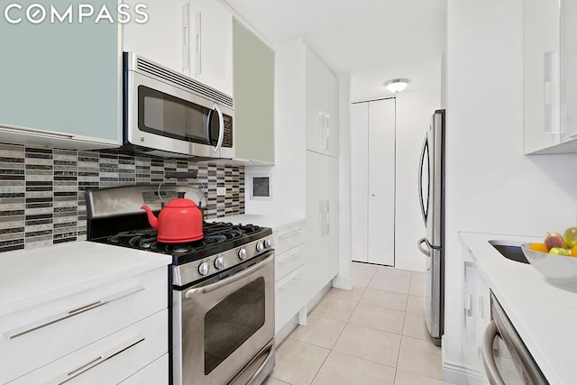 kitchen featuring tasteful backsplash, white cabinetry, stainless steel appliances, and light tile patterned flooring