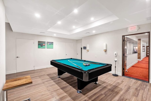 rec room with pool table, light wood-type flooring, and a tray ceiling