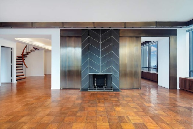 interior space featuring parquet flooring, a large fireplace, radiator, and elevator