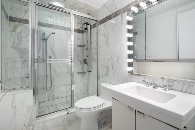 bathroom with a shower with door, vanity, tile walls, and toilet