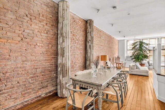 dining space with light hardwood / wood-style flooring and brick wall