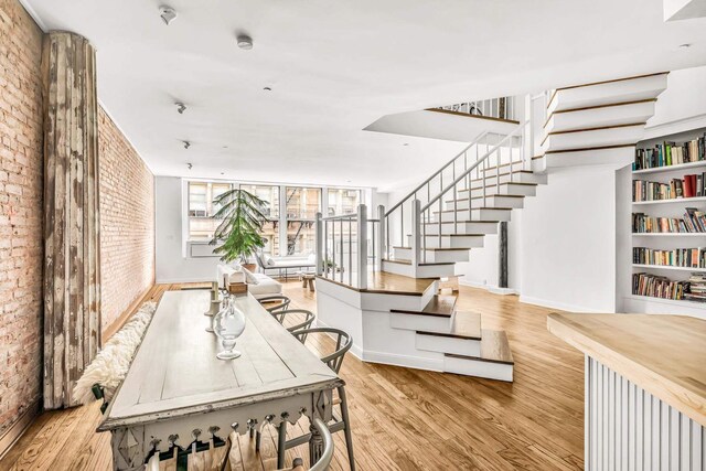 dining room with brick wall and light wood-type flooring