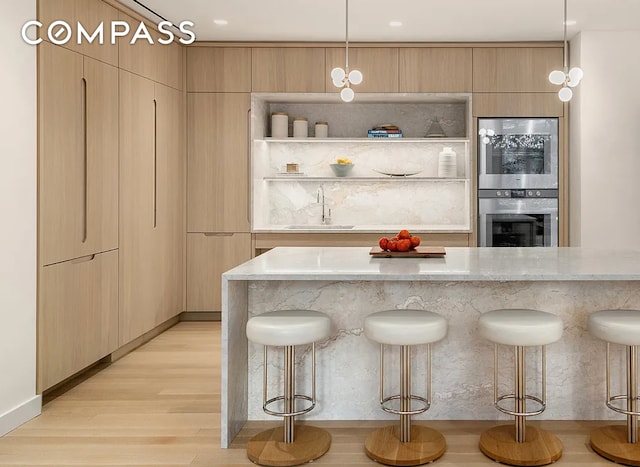 kitchen with a breakfast bar, a sink, and light stone countertops