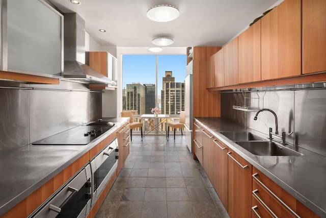 kitchen featuring decorative backsplash, wall chimney exhaust hood, black electric stovetop, a city view, and a sink