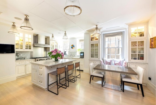 kitchen with a kitchen island, decorative backsplash, pendant lighting, and wall chimney range hood