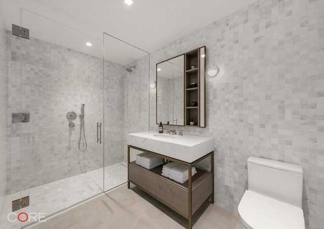 bathroom with tile walls, sink, a shower with shower door, and toilet