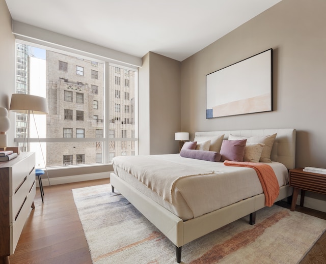 bedroom with a large fireplace, multiple windows, and wood finished floors