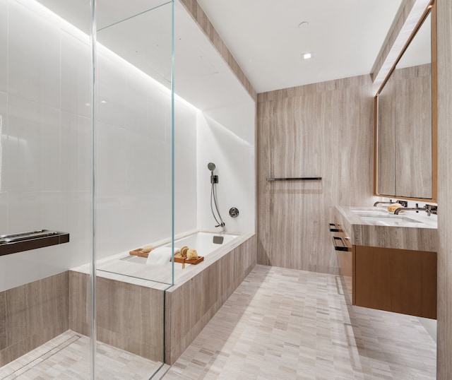 full bath featuring a tub to relax in, a sink, tiled shower, tile patterned floors, and double vanity