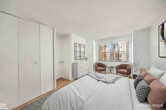 bedroom with a textured ceiling, a closet, and light parquet floors