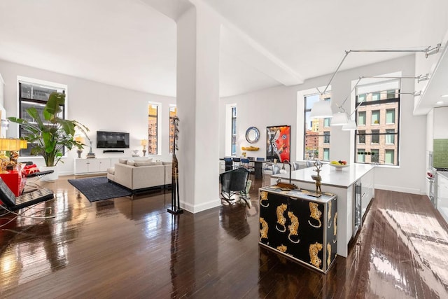 kitchen with wine cooler, dark wood-type flooring, an island with sink, and white cabinetry