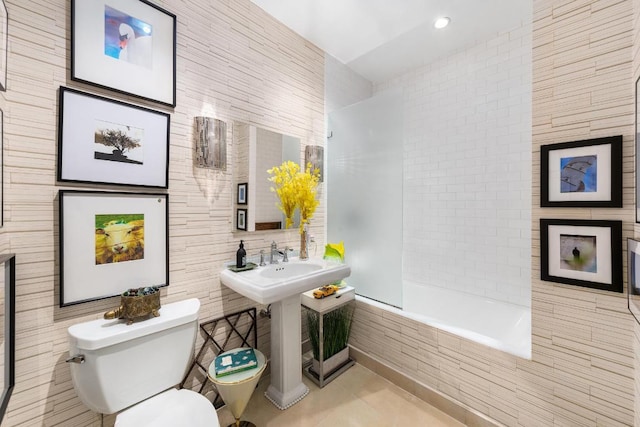 bathroom featuring tiled shower / bath, tile walls, and toilet