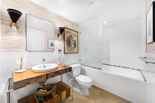 bathroom with tile patterned floors, toilet, sink, tile walls, and tiled tub