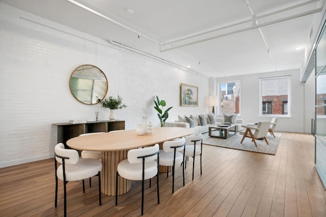 dining space with brick wall and wood-type flooring