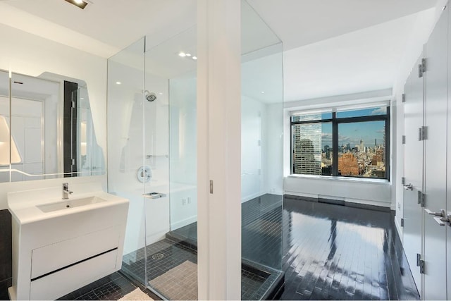 bathroom with a shower with door, hardwood / wood-style floors, and vanity