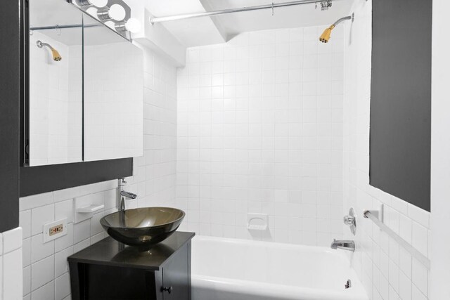 bathroom featuring tiled shower / bath, tile walls, and vanity