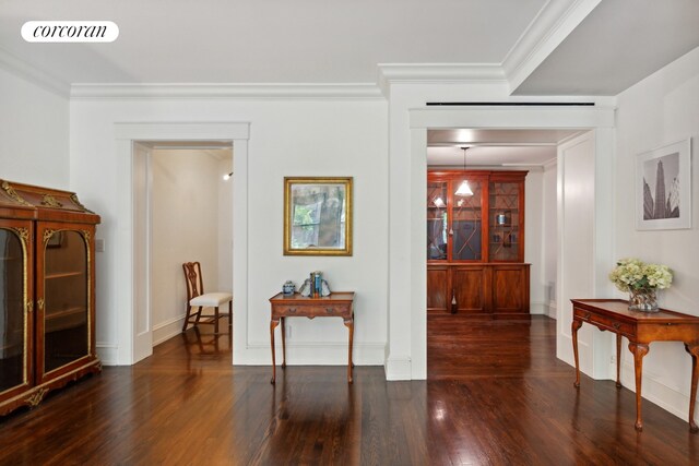 corridor with dark hardwood / wood-style floors and ornamental molding