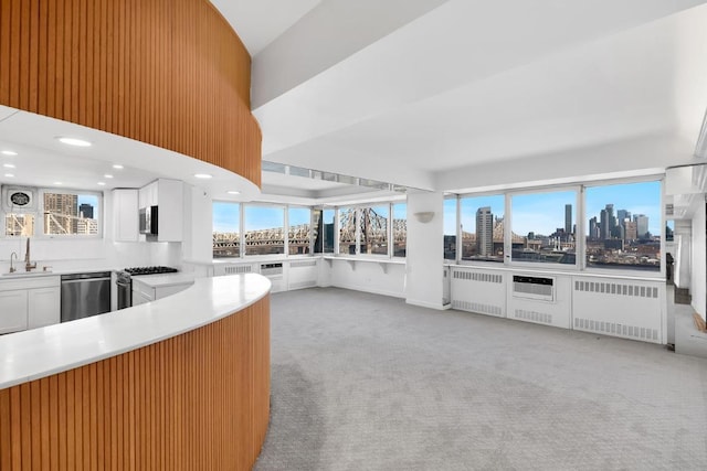 kitchen with sink, white cabinetry, light carpet, radiator heating unit, and stainless steel appliances