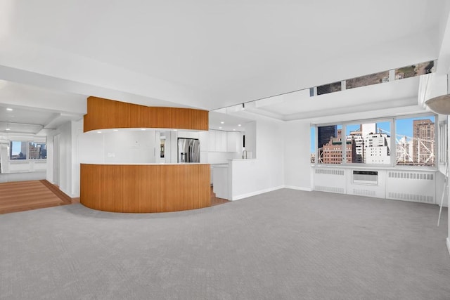 kitchen featuring stainless steel refrigerator with ice dispenser, carpet floors, radiator heating unit, and a wealth of natural light