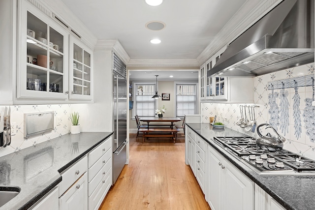 kitchen with white cabinetry, extractor fan, decorative light fixtures, and appliances with stainless steel finishes