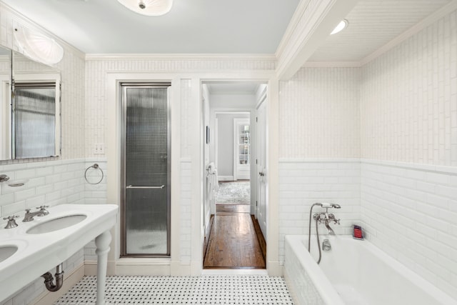 bathroom with tile walls, crown molding, tile patterned floors, and a tub