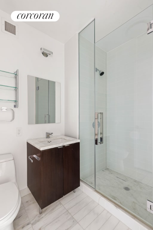 bathroom featuring vanity, toilet, and a shower with door